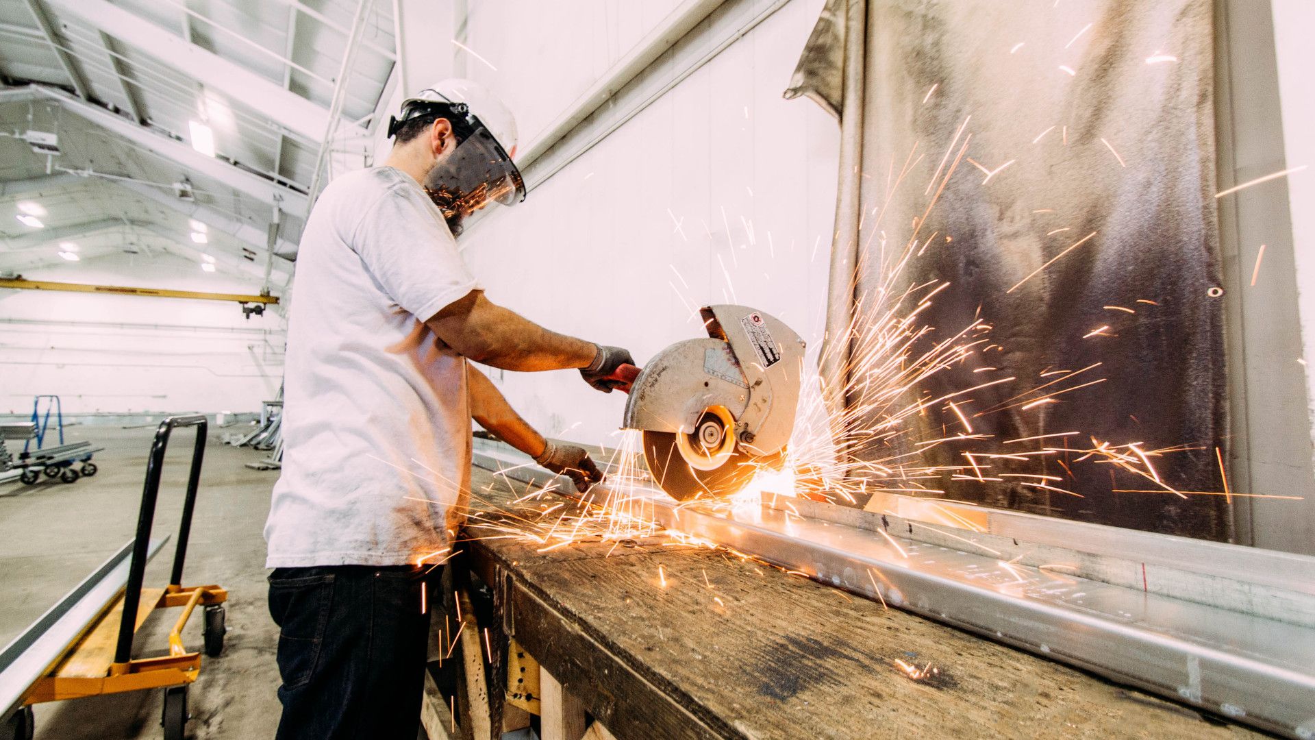 A man cuts metal with a circular saw.